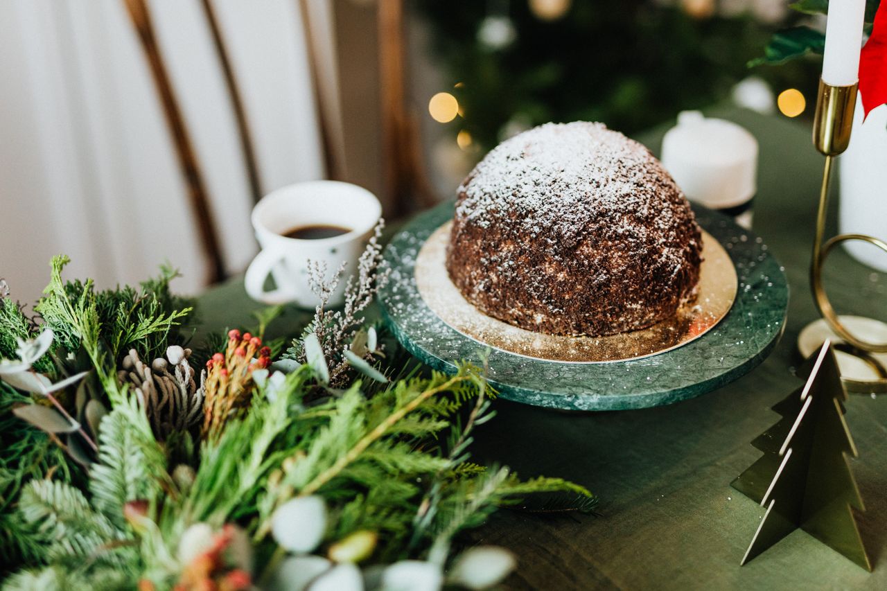 The Art of Drawing Readers In: Your attractive post title goes here Festive Christmas pudding with coffee served on a green table, adorned with seasonal decorations.